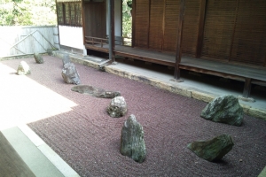 不離の庭。横たわる子供を守る２匹の犬＝丸い石