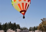 歓声が聞こえる大人気の熱気球係留フライト。見学客も気球の迫力に見上げています。